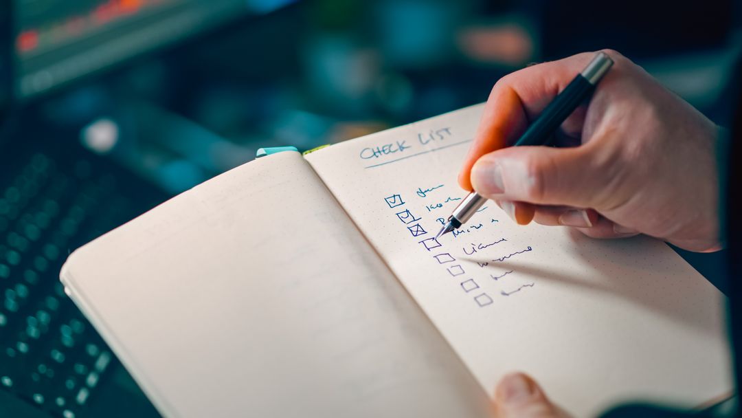Close-up of a hand writing a checklist in a notebook