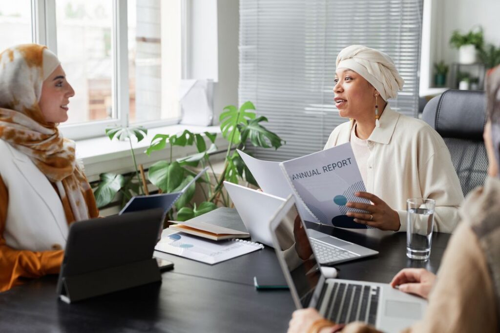 Businesswomen discussing an annual report in a modern office, representing stakeholder trust in carbon disclosure