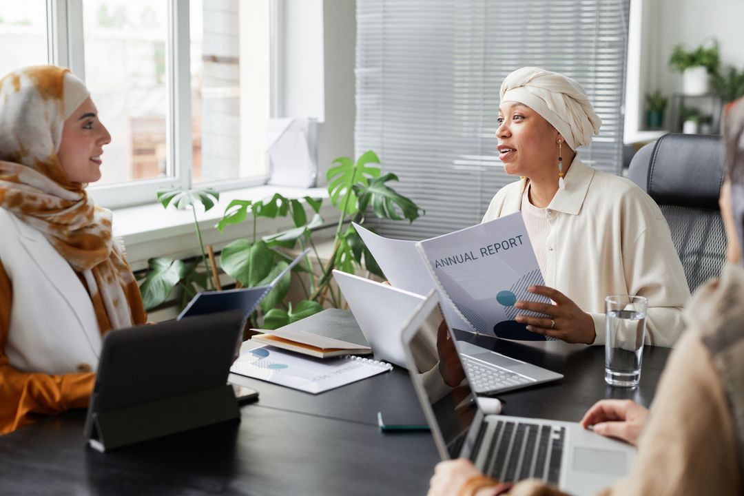 Businesswomen discussing an annual report in a modern office, representing stakeholder trust in carbon disclosure