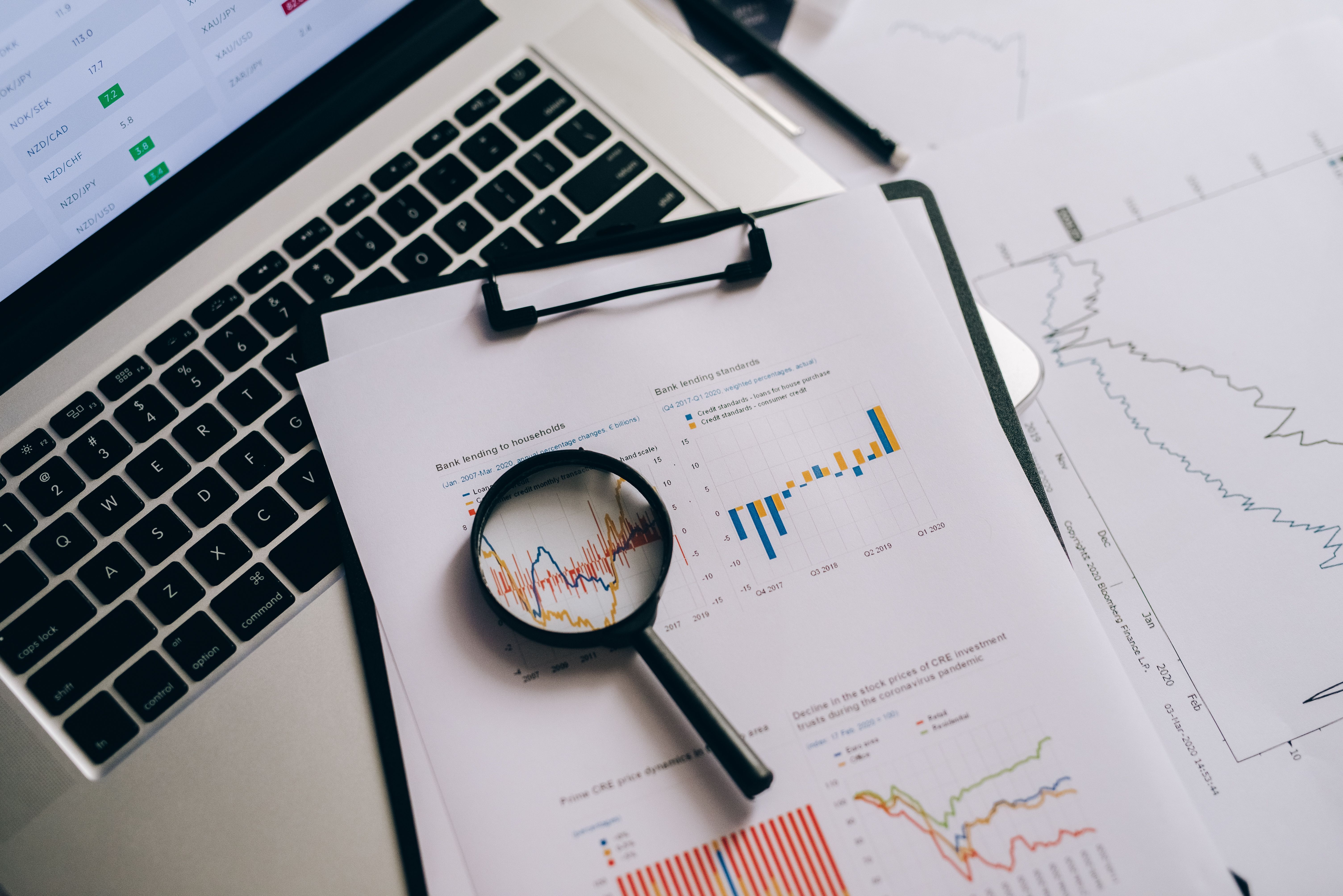 Magnifying glass over printed statistical charts, representing checking data quality to avoid carbon accounting mistakes