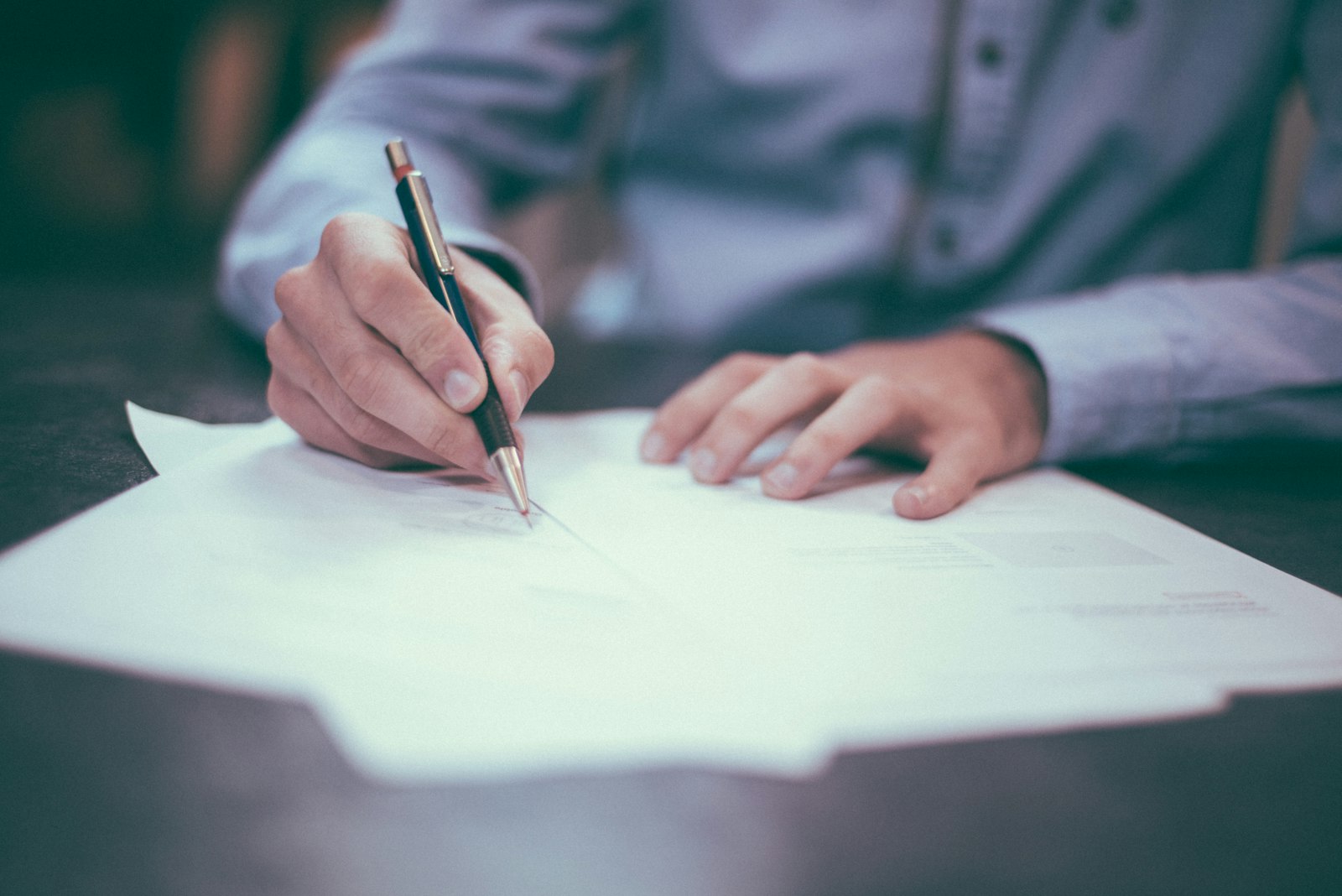 A hand signing a document, representing sign-off on verified carbon accounting records