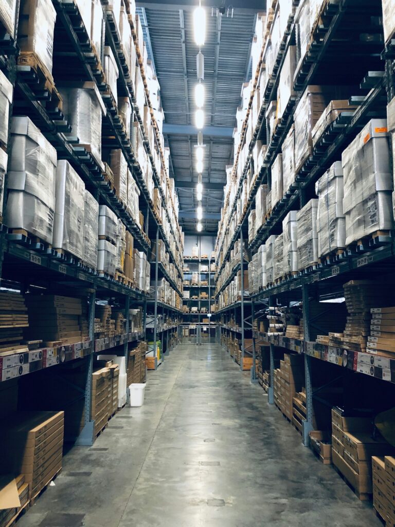 Rows of stocked warehouse shelving representing the operations businesses track for carbon accounting