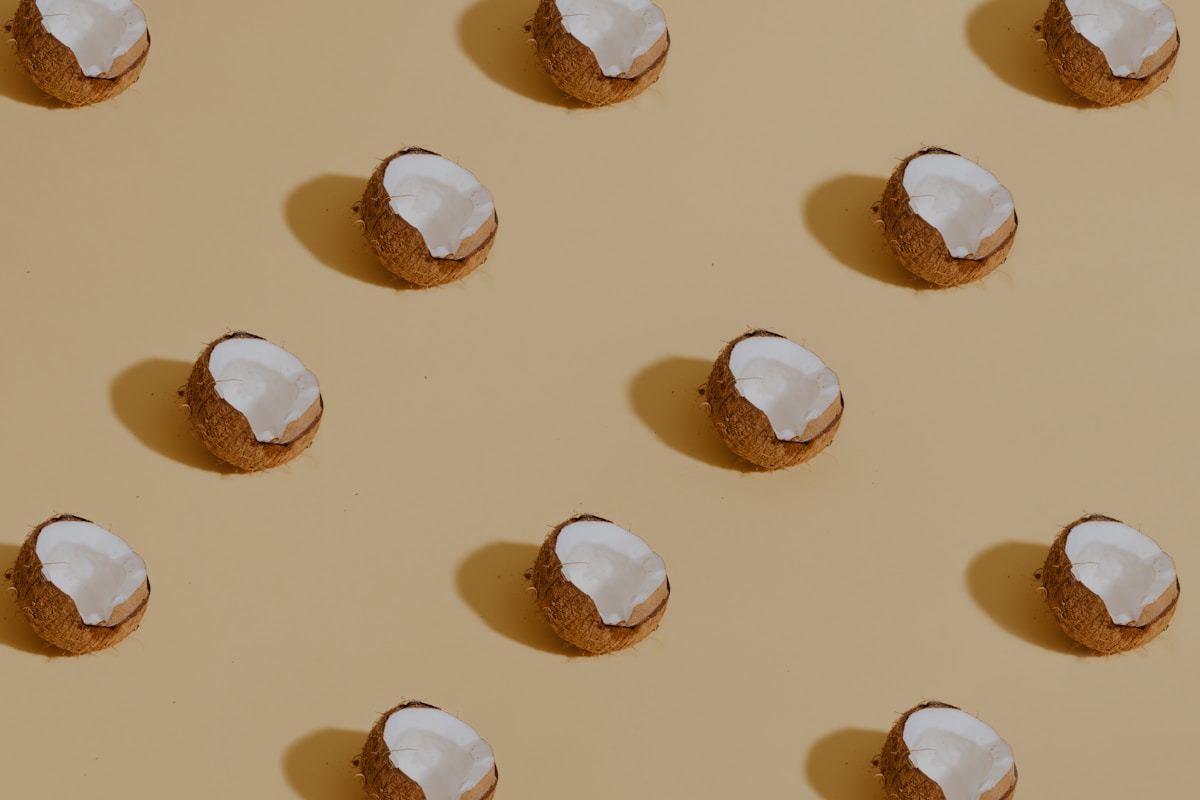 Halved coconuts showing fresh white flesh in a flat lay