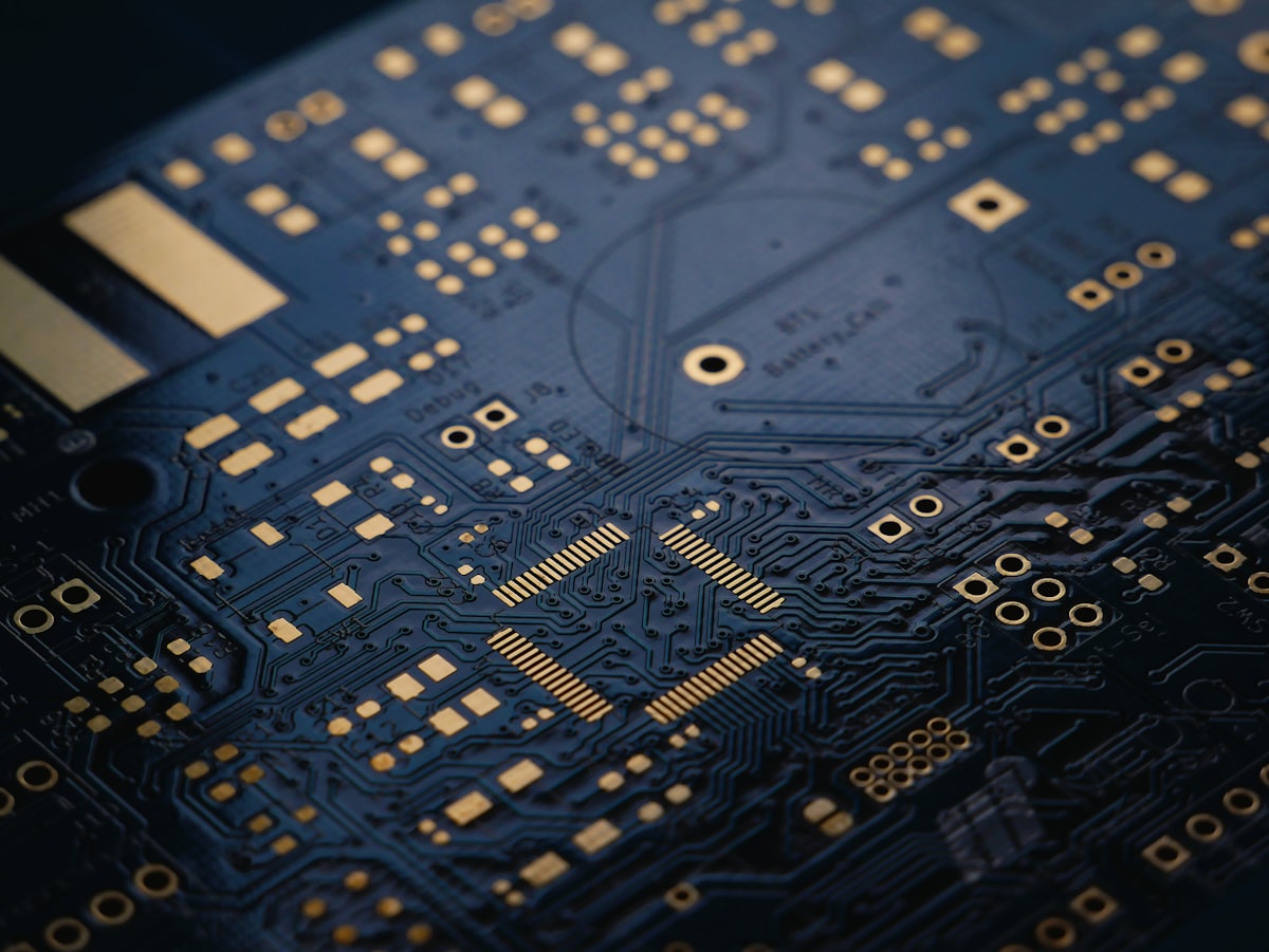 Macro close-up of a blue printed circuit board with gold contacts, representing the electronics and testing equipment used in battery material research