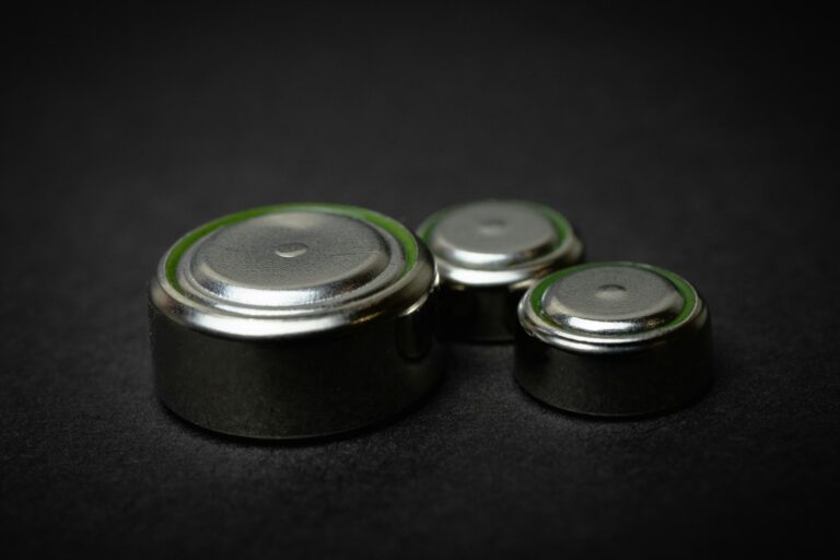 Close-up of three coin-cell batteries on a black background, representative of the coin-cell battery format used to test the new cobalt-free organic battery material