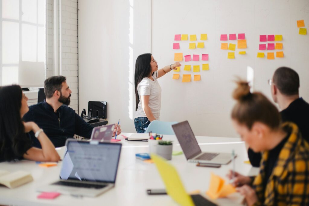 Team member placing sticky notes on a wall while colleagues look on, mapping out a carbon reduction target and roadmap