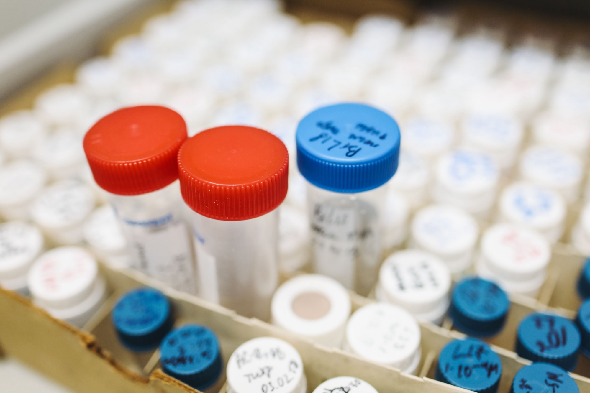 Close-up of laboratory test tubes with color-coded caps, representing battery materials science research
