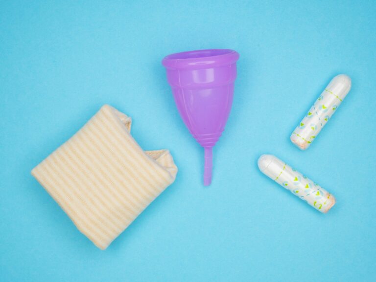 Reusable menstrual cup beside a cloth pad and tampons, showing sustainable period product alternatives