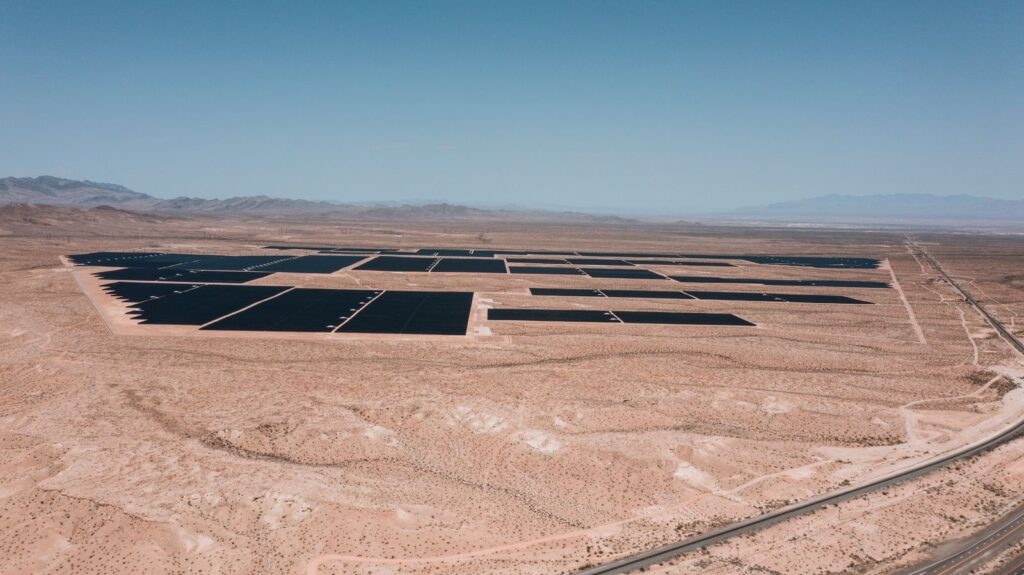 Rows of solar panels at a large utility-scale solar park under a clear blue sky
