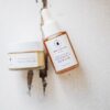 Natural organic skincare face balm and vitamin C serum bottles on a rustic white wooden background