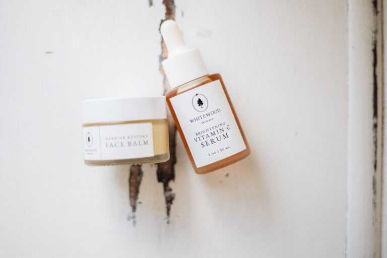 Natural organic skincare face balm and vitamin C serum bottles on a rustic white wooden background