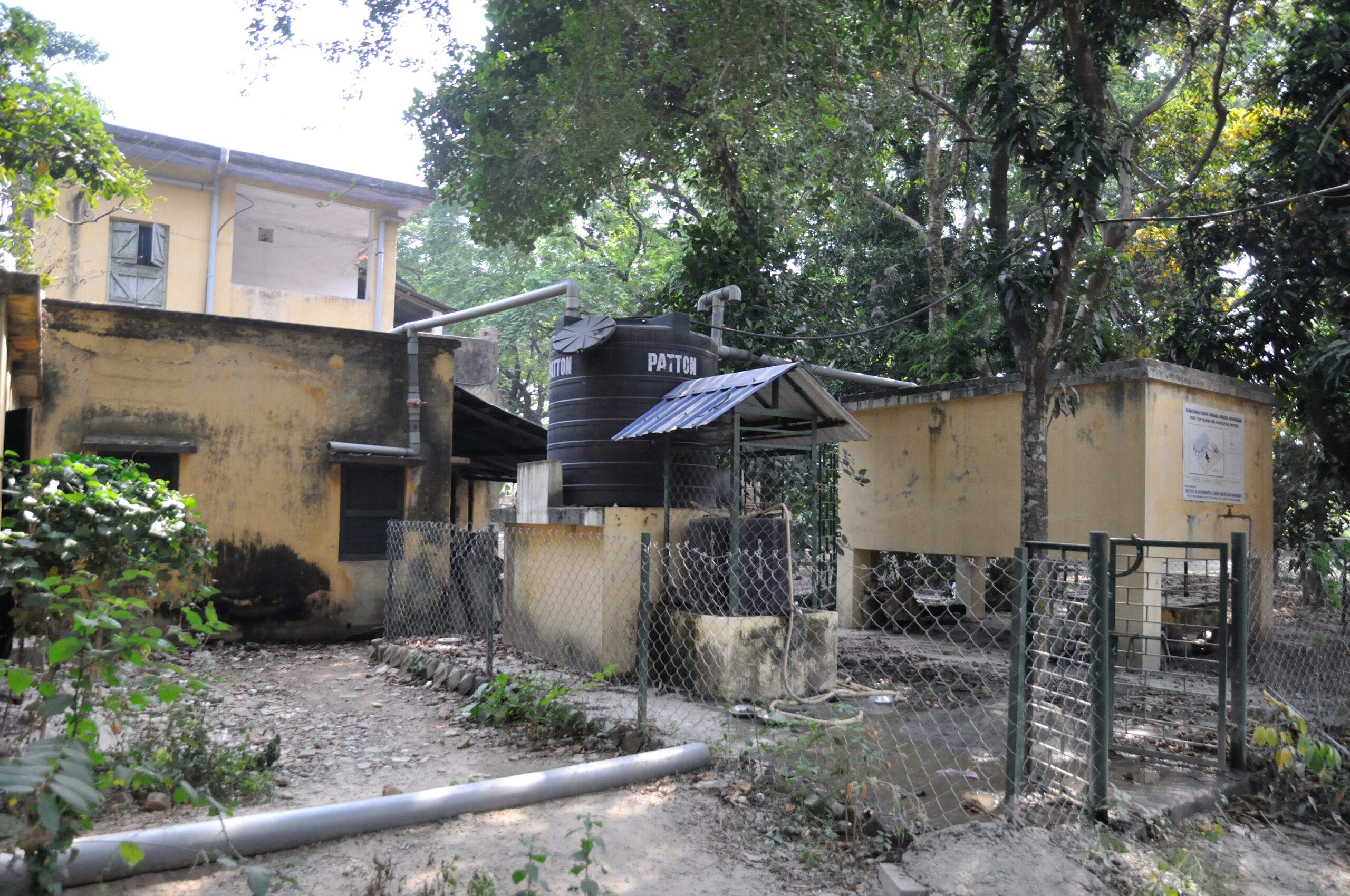 Rooftop rainwater harvesting system with pipes directing rainwater to a storage tank in India