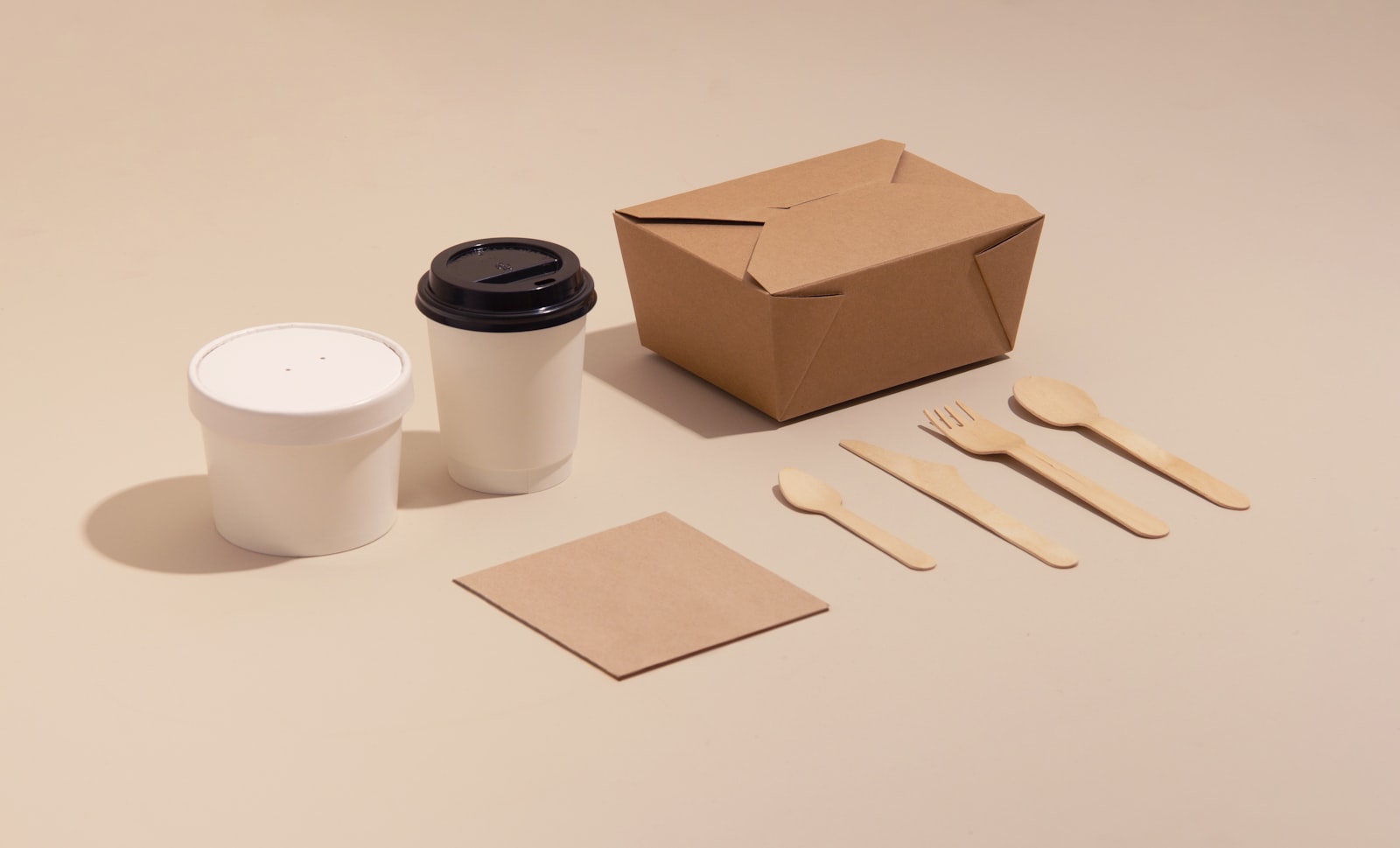 Compostable paper food containers, coffee cups and wooden cutlery representing sustainable packaging alternatives