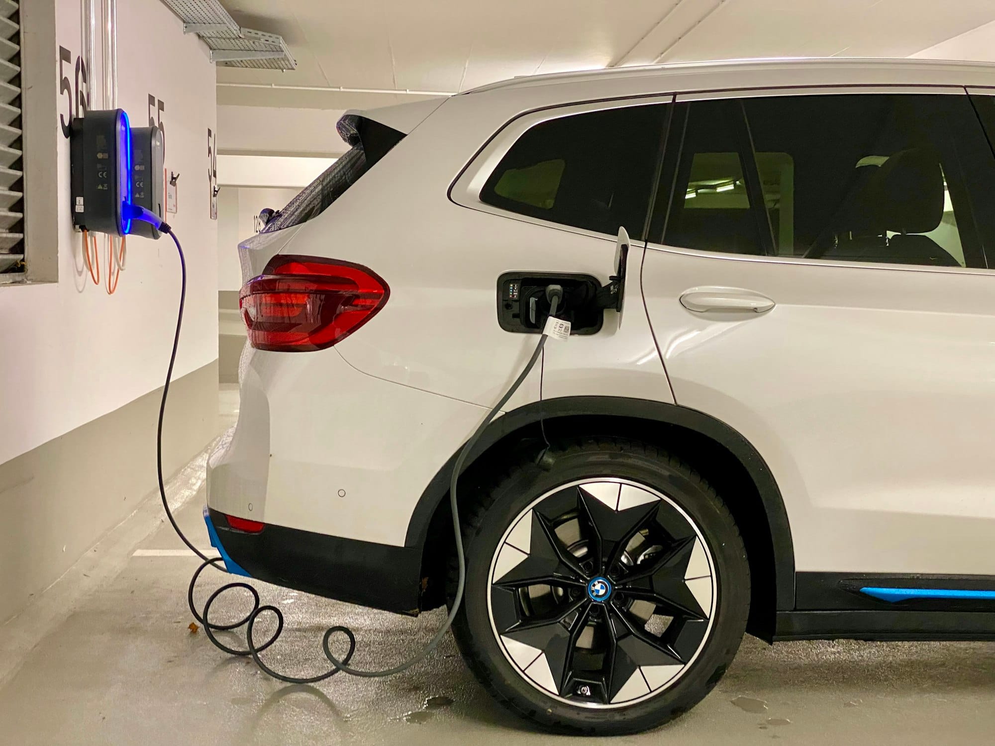 Home EV wallbox charger installed in a parking garage charging an electric car