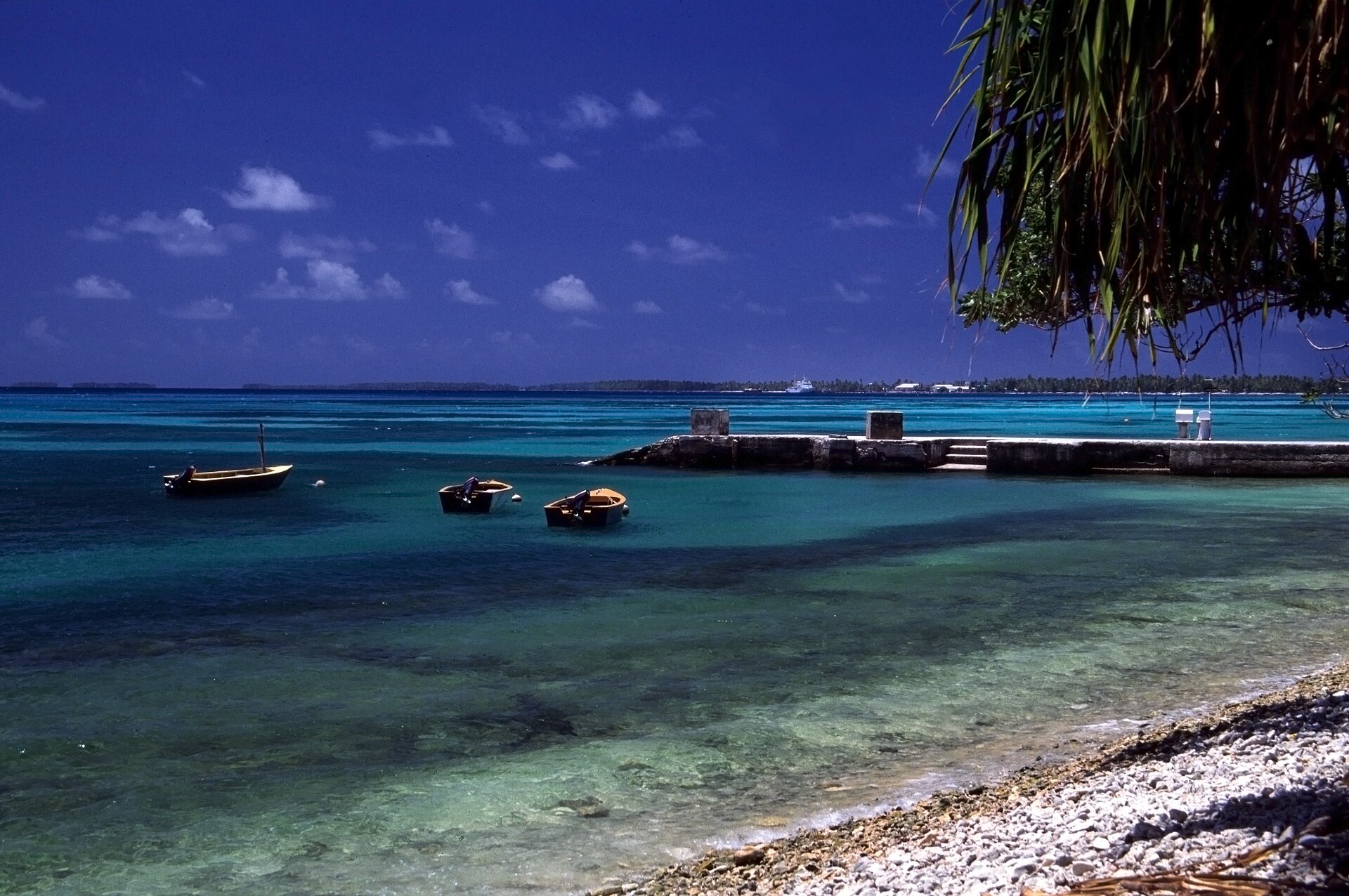 Turquoise lagoon, small boats and a concrete jetty on the coast of Funafuti Atoll, Tuvalu