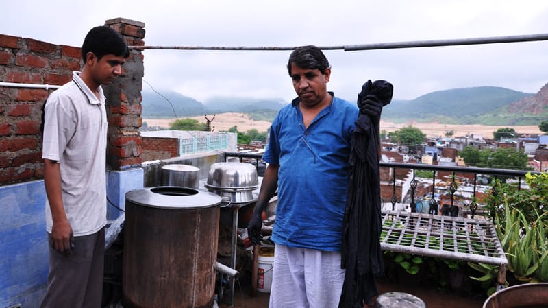 Artisan in Jaipur holding freshly dyed cloth beside a traditional dyeing vessel